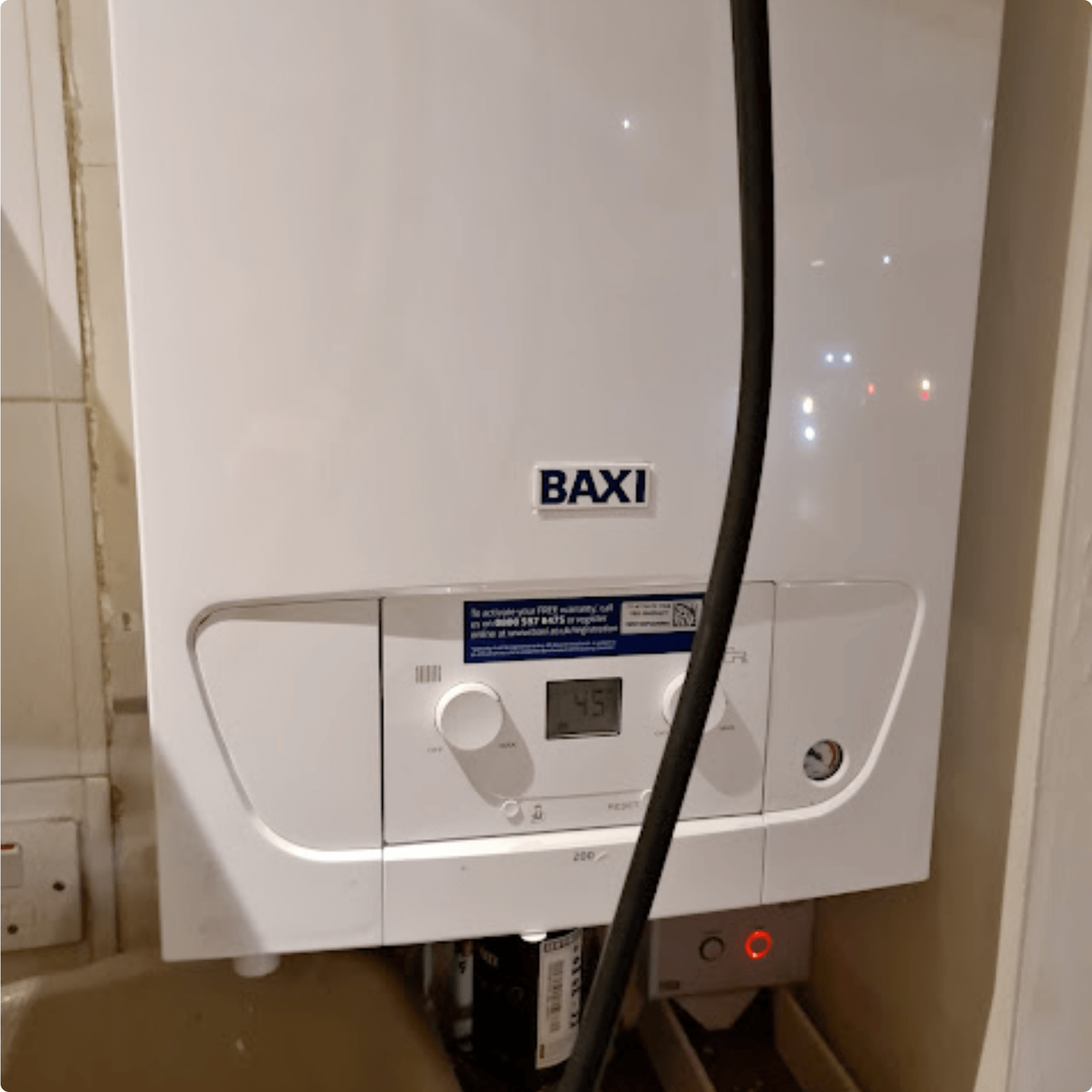 Alt text: "A Baxi boiler mounted on a wall, featuring a digital display showing 45 degrees. The boiler is white with a clean, modern design."